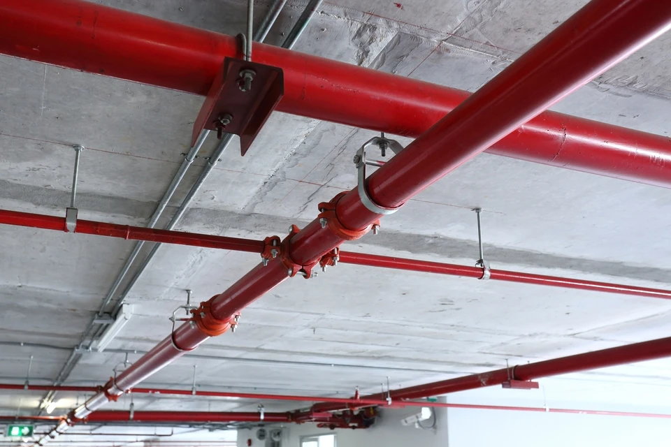 Scène extérieure d'installation industrielle avec canalisation principale orange de grand diamètre équipée de vannes de sectionnement